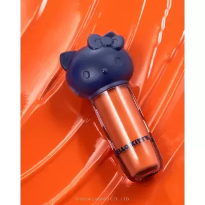 Frasco de cosmético laranja com tampa azul em forma da Hello Kitty sobre fundo laranja