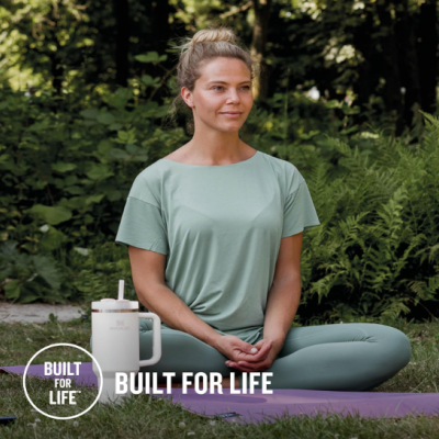 Mulher a fazer yoga com roupa verde e caneca ao lado