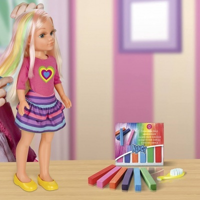 Boneca com cabelo multicolorido e caixa de giz de cabelo em cima de mesa