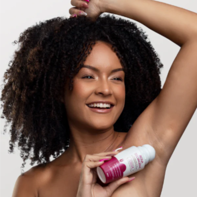 Mulher com desodorizante roll-on próximo à axila, fundo branco