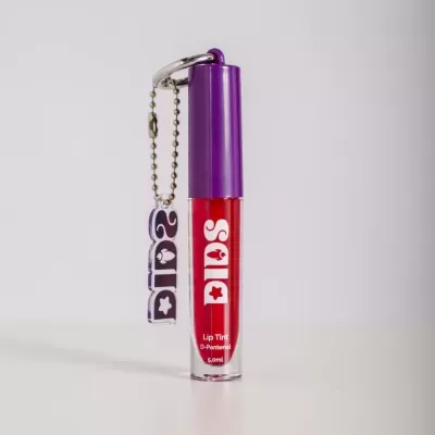 Lip Tint em embalagem transparente com tampa roxa e líquido vermelho, pendente roxo com chave metálica