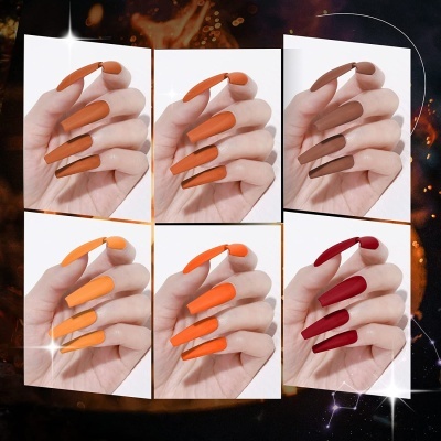 Unhas longas com esmalte mate em tons de laranja, castanho e vermelho