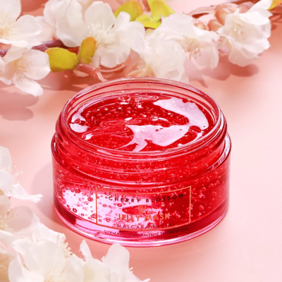 Pote de gel vermelho com rótulo e flores ao redor, sobre fundo rosa