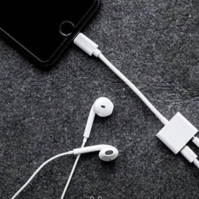 Smartphone preto com carregador e auscultadores brancos sobre fundo cinzento