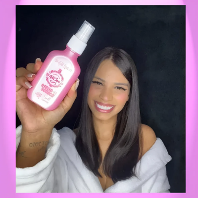 Mulher sorridente segurando frasco rosa de spray Efeito Seda