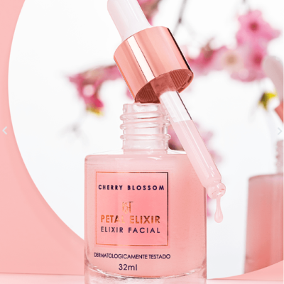 Frasco de elixir facial rosa com conta-gotas e flores de cerejeira ao fundo