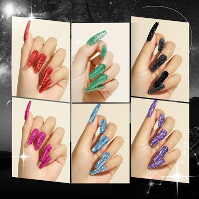 Unhas compridas com verniz brilhante e glitter em várias cores diferentes sobre fundos claros.