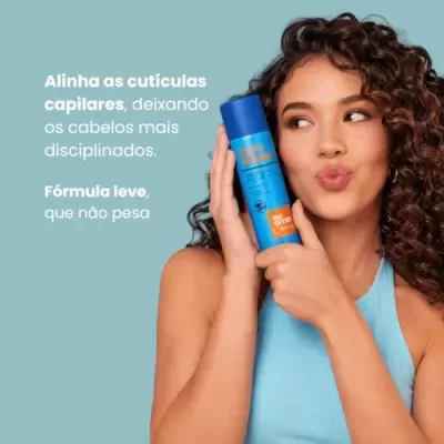 Mulher com cabelo encaracolado segurando frasco azul e laranja de produto capilar Niely
