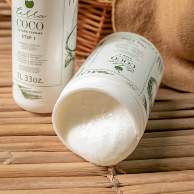 Frascos de produto capilar branco Tesla COCO com creme derramado sobre madeira.