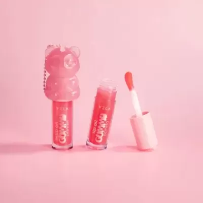 Dois frascos pequenos de lip oil rosa com tampa em forma de urso e aplicador aberto sobre fundo rosa