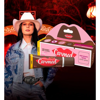 Hidratante labial Carmed em tubo vermelho e embalagem colorida com modelo vestindo chapéu branco e casaco jeans azul
