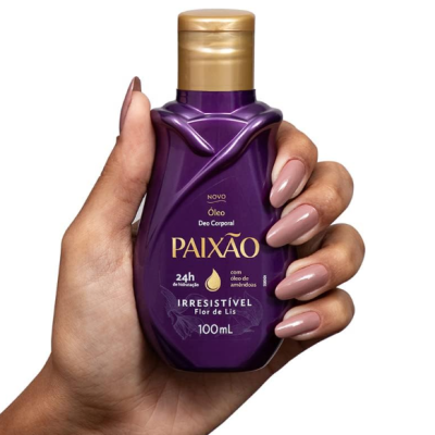 Frasco roxo de óleo corporal PAIXÃO segurado por mão