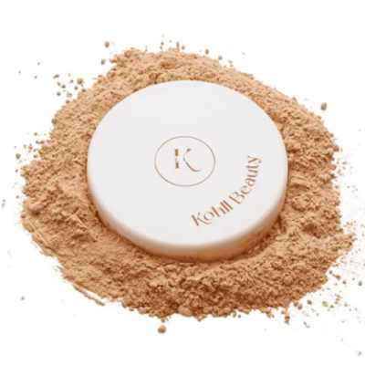 Pó compacto cosmético branco com texto Kohli Beauty rodeado por pó solto bege claro