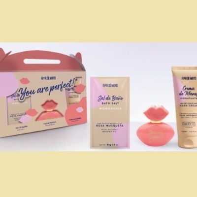 Conjunto de produtos para banho em tons de rosa e bege com embalagem decorativa e textos visíveis.