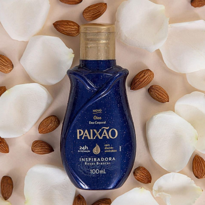 Frasco azul de óleo corporal Paixão com pétalas de rosa brancas e amêndoas ao redor