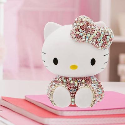 Figura decorativa Hello Kitty brilhante em tons rosa e dourado sobre cadernos cor-de-rosa