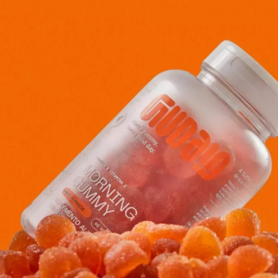 Frasco translúcido com gomas laranjas e rótulo com texto em inglês sobre fundo laranja