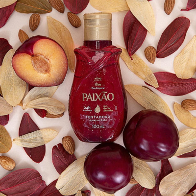 Frasco de óleo corporal Paixão rodeado por folhas secas, amêndoas e ameixas