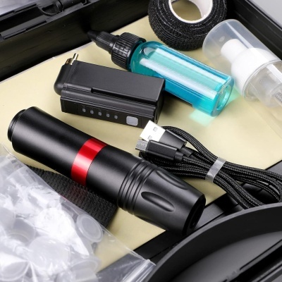 Conjunto de aparelhos e acessórios para tatuagem num estojo preto.