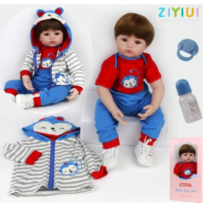 Dois bonecos bebês com roupas infantis azuis e vermelhas, casaco riscado cinza e branco com capuz de macaco, chupeta e biberão azul.