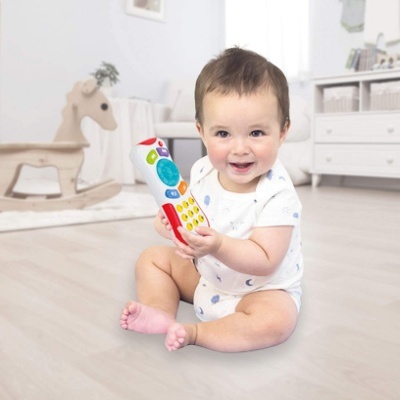 Bebé sentado no chão com brinquedo colorido em forma de telefone