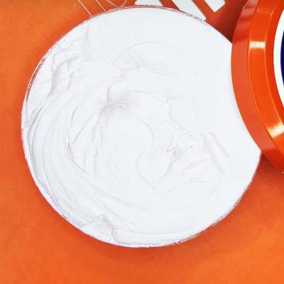 Creme branco em frasco redondo aberto laranja com rótulo azul e branco