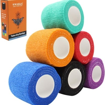 Seis rolos de bandagem adesiva para tatuagens em várias cores com embalagem laranja ao lado.