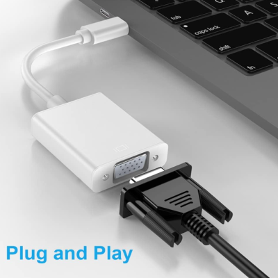 Adaptador USB-C para VGA branco junto a portátil e conector VGA preto, texto 'Plug and Play'
