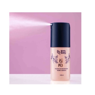 Frasco de fixador de maquilhagem Bana Flowers com pulverizador activo em fundo rosa.