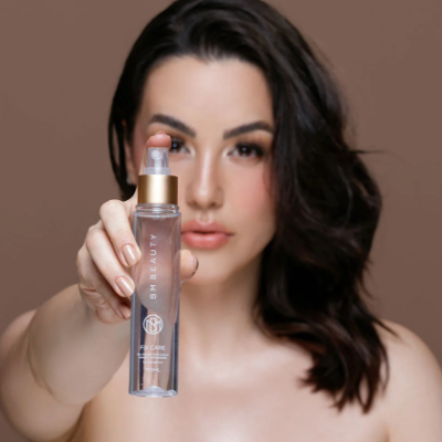 Mulher segurando spray cosmético BH BEAUTY com tampa dourada