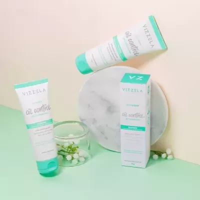 Produtos Vizzela oil control para cuidado da pele em tubo e caixa, com decoração de flores brancas e prato marmoreado.