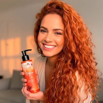 Mulher com cabelo ruivo a segurar frasco laranja com tampa bomba
