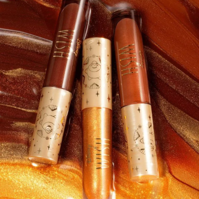 Três glosses labiais metálicos castanho, dourado e laranja com tampas decoradas em fundo marmoreado castanho e dourado