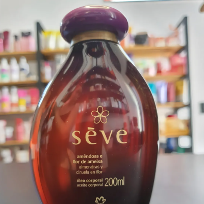Frasco oval castanho com tampa roxa, óleo corporal Sève 200ml em prateleira.