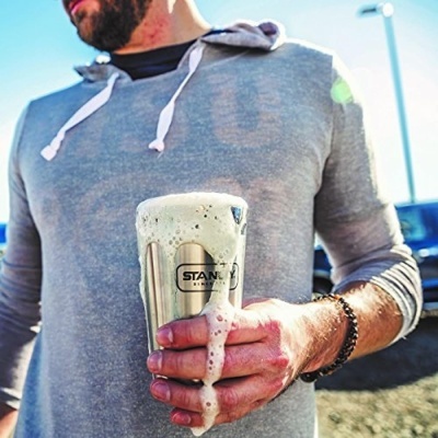 Homem segurando copo térmico de metal com espuma a transbordar