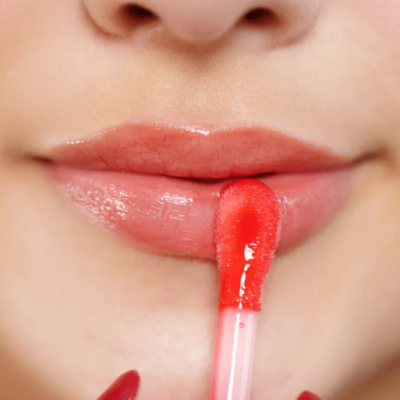 Aplicação de batom líquido vermelho coral nos lábios