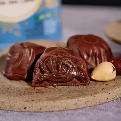 Bombons de chocolate com recheio cremoso sobre prato de pedra, com noz ao lado.