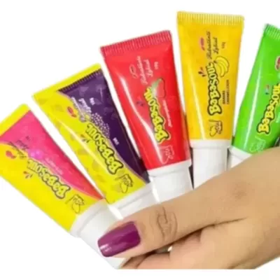 Tubos coloridos de creme BeBoSouL segurados por mão com unha roxa