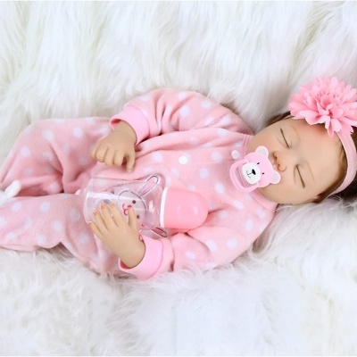 Boneca bebé em fato rosa com bolinhas brancas e fita de cabelo com flor