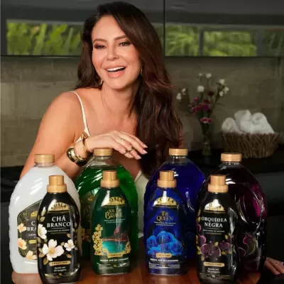 Garrafas de amaciantes COALA em diferentes cores e aromas com mulher sorridente ao fundo