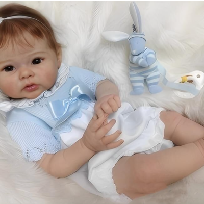 Boneca realista vestida de azul e branco com brinquedos ao lado