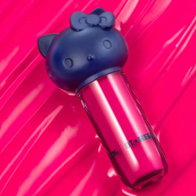 Batom com tampa de cabeça de gato preto e corpo rosa metálico sobre fundo rosa brilhante