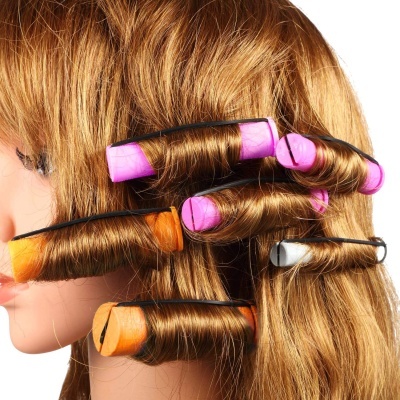 Cabelo castanho enrolado em papéis mágicos coloridos presos por grampos numa cabeça de manequim