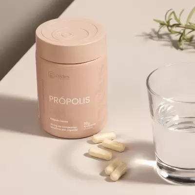 Frasco de suplemento de própolis bege com cápsulas e copo de água