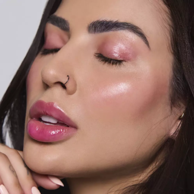 Rosto de mulher com maquilhagem rosa e anel na narina