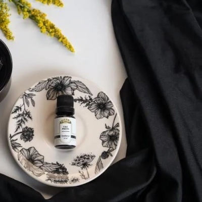 Frasco de óleo essencial numa prato branco com flores desenhadas a preto