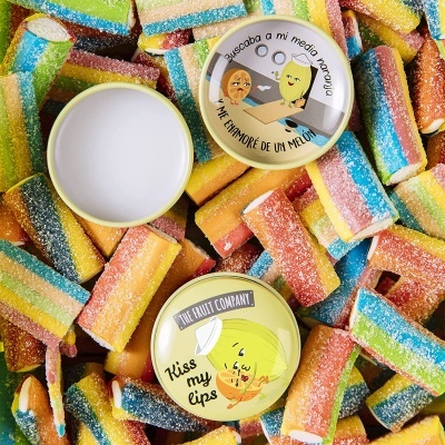 Duas latas redondas de bálsamo labial sobre doces multicoloridos açucarados.