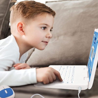 Criança utilizando um computador portátil branco sentado num sofá cinza com um rato branco e azul junto.