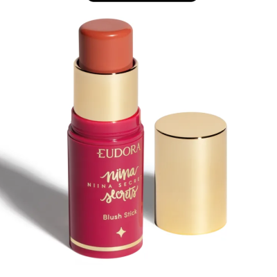 Blush stick cor salmão em embalagem vermelha com tampa dourada ao lado