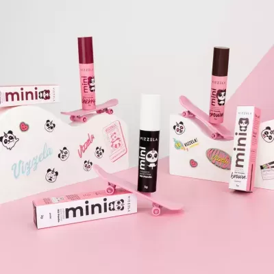 Produtos Vizzela mini em caixas retangulares com urso panda e textos, sobre skates rosa em fundo rosa e branco decorado